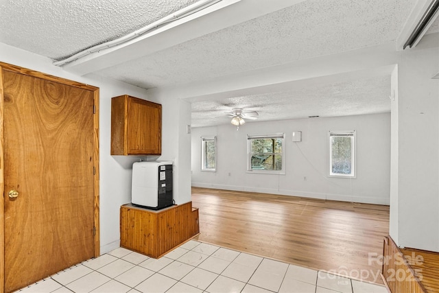 kitchen with brown cabinets, a ceiling fan, light wood-style floors, open floor plan, and a textured ceiling