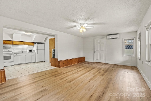 unfurnished living room with a textured ceiling, a sink, a ceiling fan, light wood-style floors, and a wall mounted AC