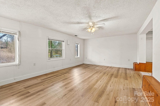 unfurnished room featuring light wood-style floors, ceiling fan, baseboards, and a textured ceiling