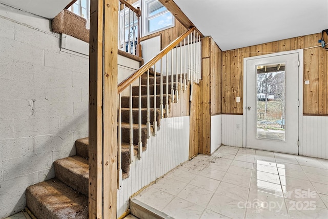 doorway to outside featuring concrete block wall, wood walls, and stairs