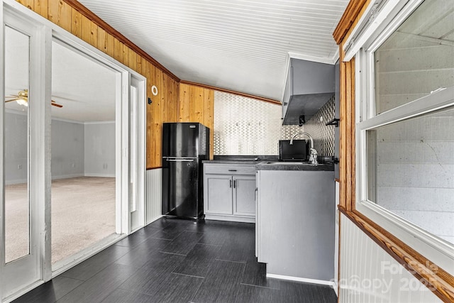 kitchen with crown molding, freestanding refrigerator, a sink, and dark countertops