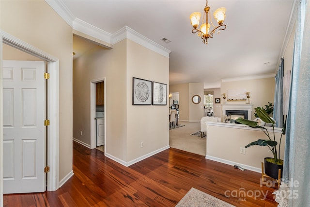 corridor with visible vents, a notable chandelier, wood finished floors, and crown molding