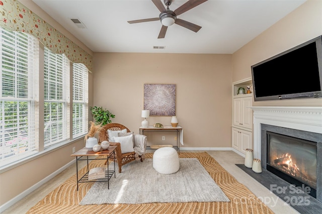 sitting room featuring light carpet, visible vents, baseboards, and a ceiling fan