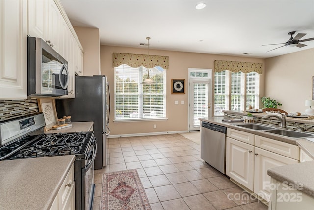 kitchen featuring tasteful backsplash, ceiling fan, light tile patterned floors, stainless steel appliances, and a sink