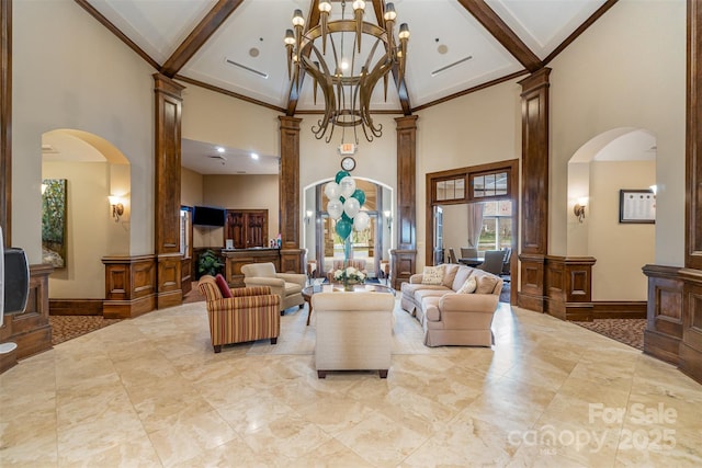 living area featuring beam ceiling, a high ceiling, arched walkways, and ornamental molding