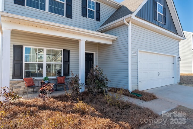 view of exterior entry featuring a garage, covered porch, and board and batten siding