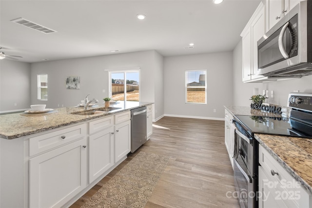 kitchen featuring stainless steel appliances, visible vents, light wood-style flooring, white cabinets, and a sink