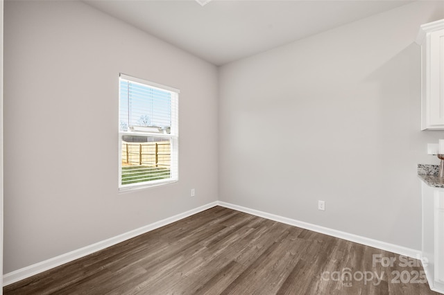 spare room with dark wood-style floors and baseboards