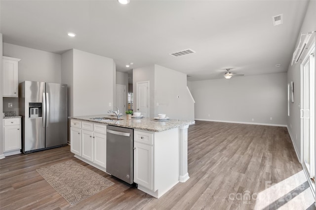 kitchen with stainless steel appliances, visible vents, a sink, and white cabinetry