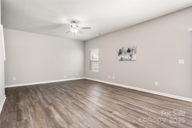 empty room with visible vents, ceiling fan, baseboards, and wood finished floors