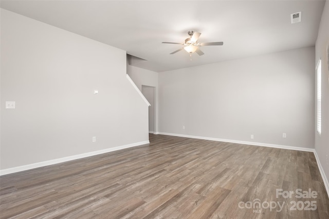 unfurnished room with ceiling fan, visible vents, baseboards, and wood finished floors