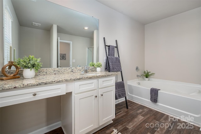 bathroom featuring visible vents, a garden tub, vanity, and wood finished floors