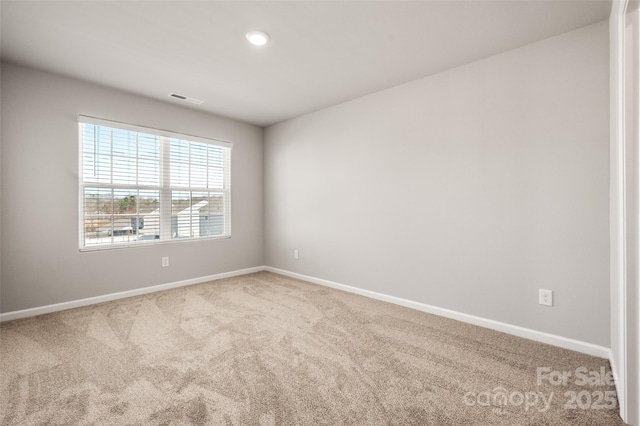 empty room with carpet, visible vents, and baseboards