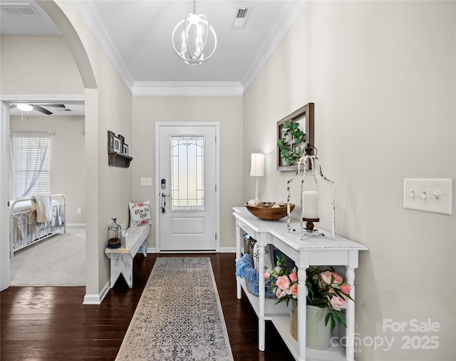 entryway with visible vents, arched walkways, dark wood-type flooring, crown molding, and ceiling fan with notable chandelier