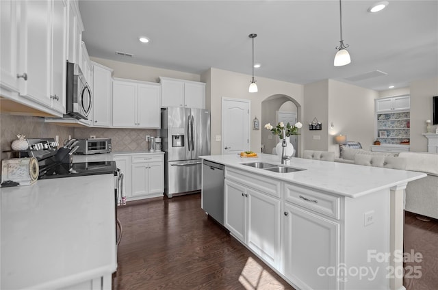 kitchen featuring white cabinets, open floor plan, dark wood-style flooring, stainless steel appliances, and a sink