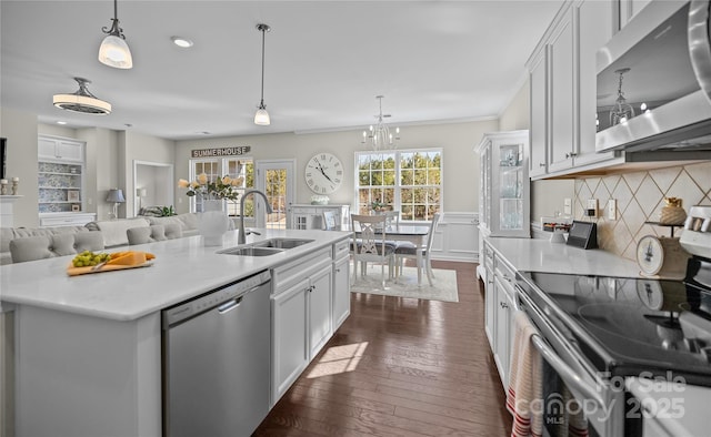 kitchen featuring appliances with stainless steel finishes, light countertops, a sink, and dark wood-type flooring