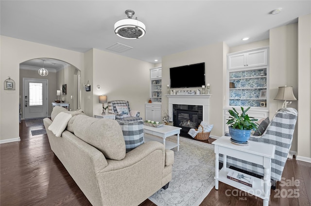 living room with arched walkways, dark wood-style flooring, visible vents, and baseboards