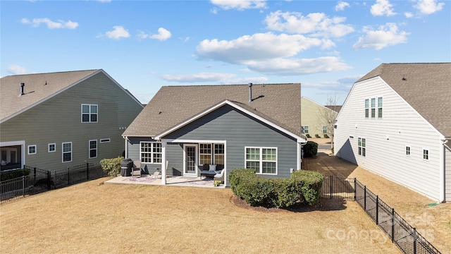 rear view of house with a shingled roof, a fenced backyard, a patio, and a lawn