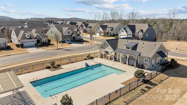 community pool featuring a patio area, a residential view, and fence