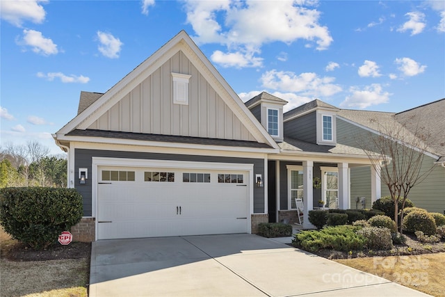 view of front of house featuring driveway, stone siding, a garage, and board and batten siding