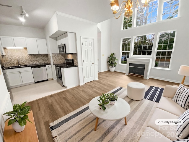 living room featuring light wood-type flooring, a fireplace, visible vents, and a chandelier