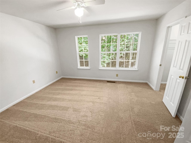 carpeted empty room featuring baseboards, visible vents, ceiling fan, and a wealth of natural light