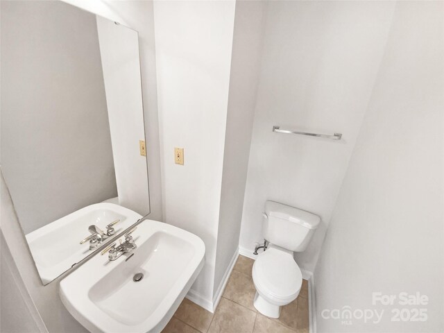 bathroom featuring tile patterned flooring, baseboards, a sink, and toilet