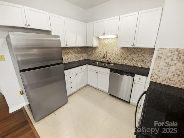 kitchen with stainless steel appliances, tasteful backsplash, a sink, and white cabinetry