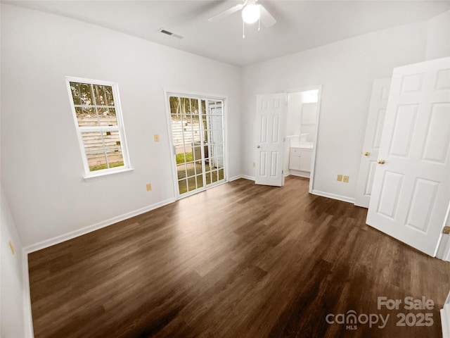 unfurnished bedroom featuring dark wood finished floors, visible vents, ensuite bathroom, ceiling fan, and baseboards