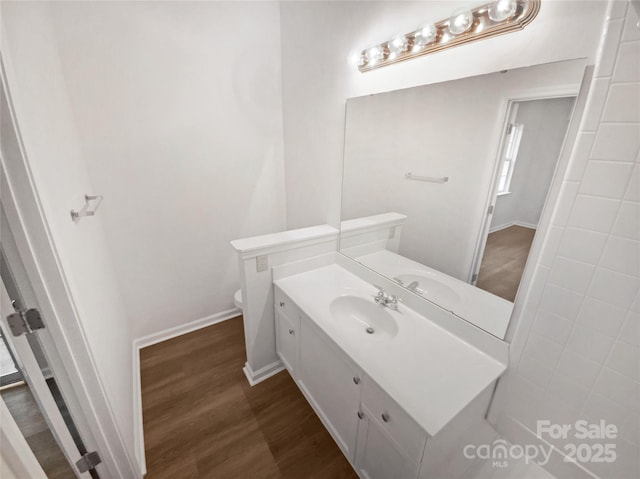 bathroom featuring toilet, baseboards, wood finished floors, and vanity