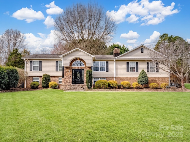 view of front of property with brick siding, a chimney, and a front yard