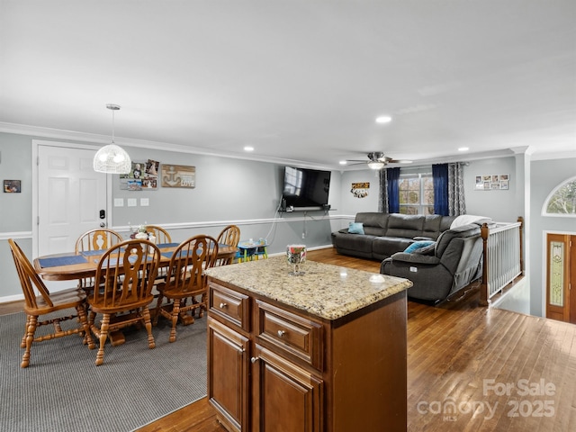 2200 Peninsula Ave, Shelby, NC 28150 - kitchen with crown molding, dark wood-style flooring, a ceiling fan, a center island, and light stone counters