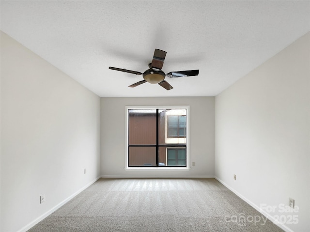 spare room featuring a ceiling fan, light carpet, and baseboards