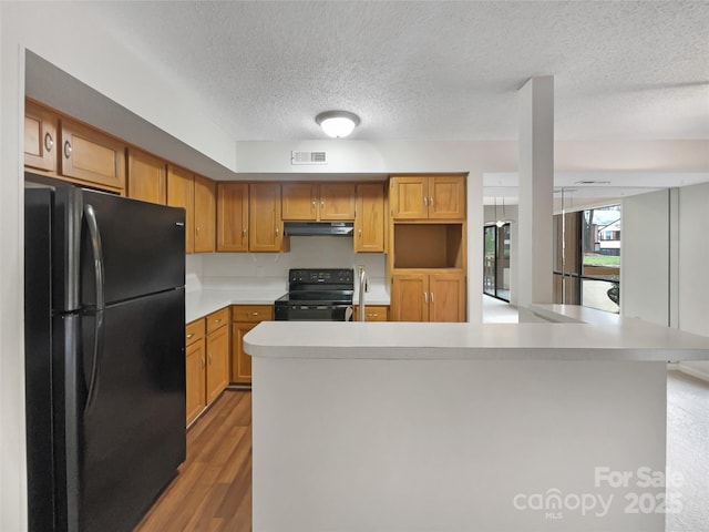 kitchen featuring black appliances, under cabinet range hood, visible vents, and light countertops