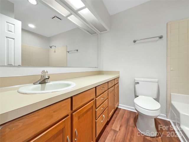 bathroom with visible vents, toilet, vanity, wood finished floors, and baseboards