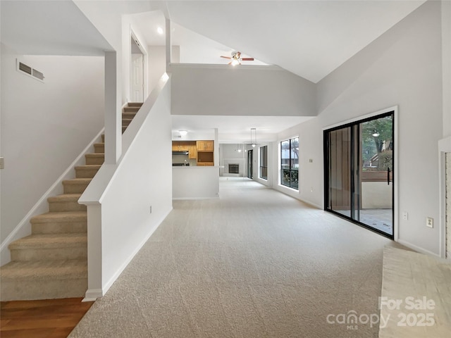 unfurnished living room with stairway, baseboards, visible vents, and a ceiling fan