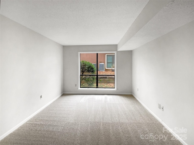 spare room with a textured ceiling, carpet floors, and baseboards