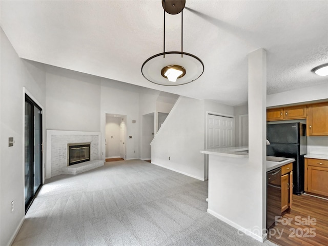 living area with baseboards, light colored carpet, a textured ceiling, and a glass covered fireplace