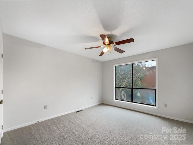 spare room featuring carpet floors, visible vents, ceiling fan, a textured ceiling, and baseboards