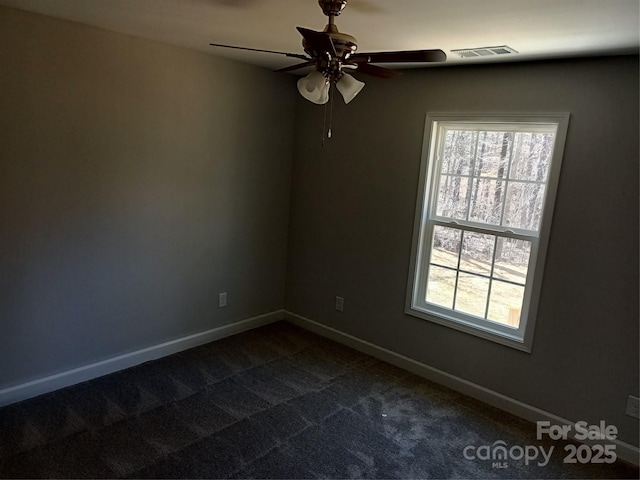 unfurnished room with dark carpet, visible vents, and baseboards