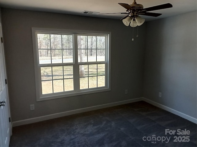 unfurnished room featuring a healthy amount of sunlight, baseboards, visible vents, and dark colored carpet