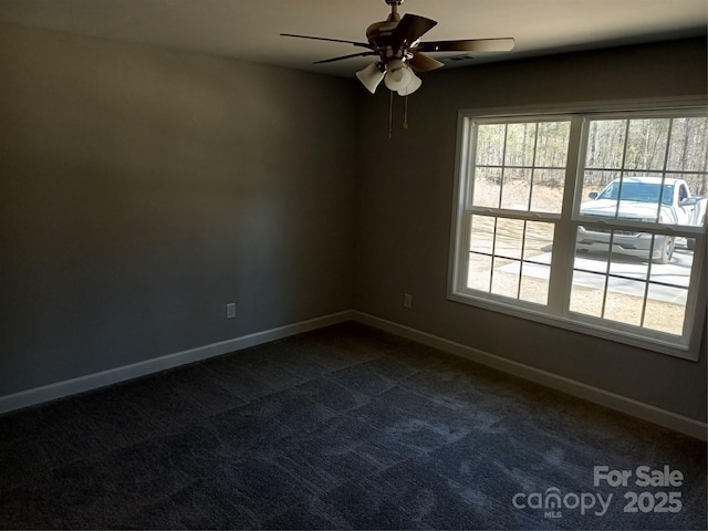 empty room featuring dark carpet, baseboards, and ceiling fan