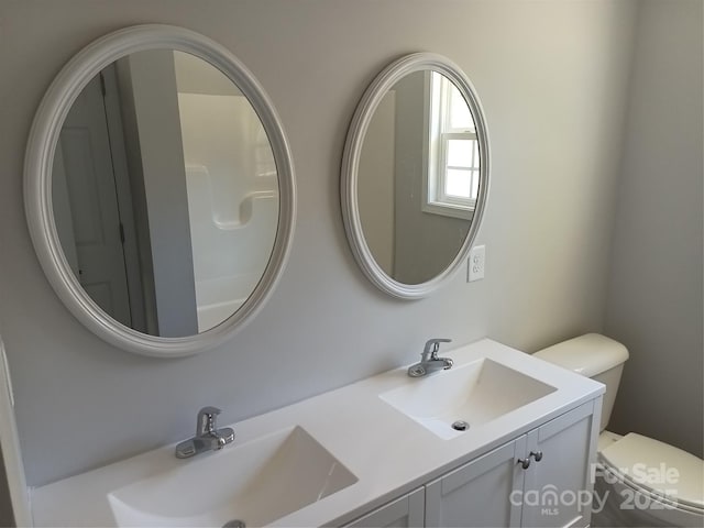 bathroom featuring a sink, toilet, and double vanity