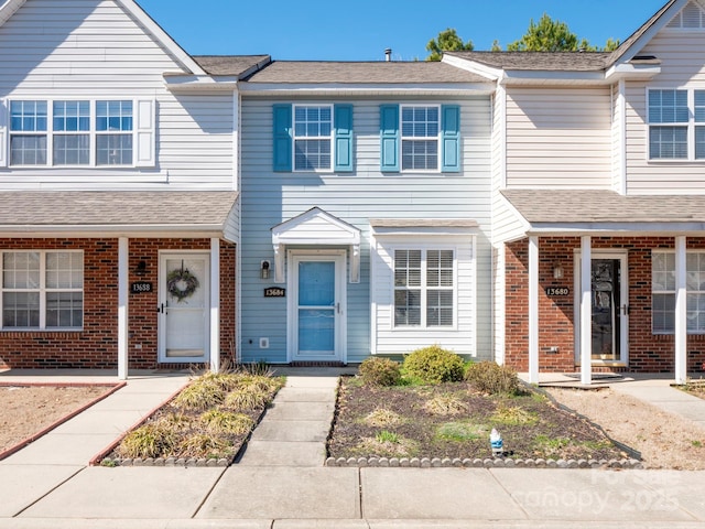 townhome / multi-family property featuring a shingled roof and brick siding