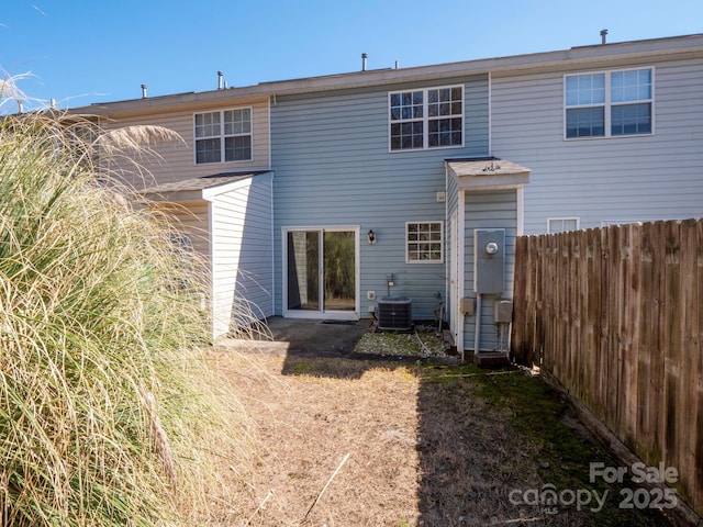 rear view of house with central AC unit and fence