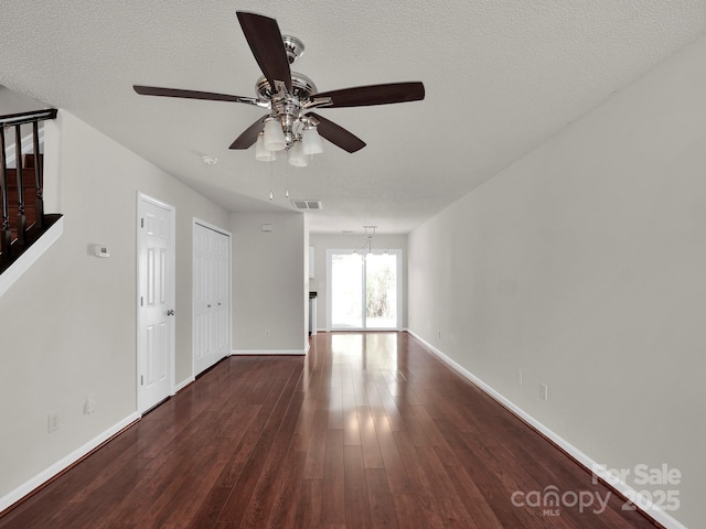 unfurnished living room with a textured ceiling, wood finished floors, visible vents, and baseboards