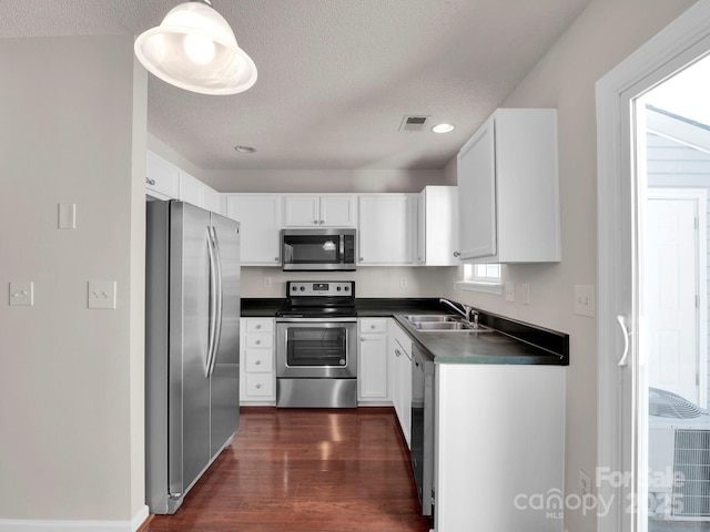 kitchen with dark countertops, visible vents, appliances with stainless steel finishes, and a sink