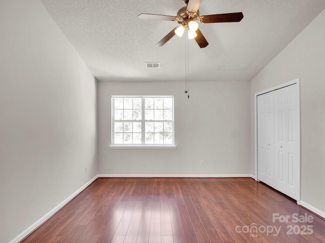 unfurnished bedroom featuring a textured ceiling, ceiling fan, wood finished floors, visible vents, and baseboards