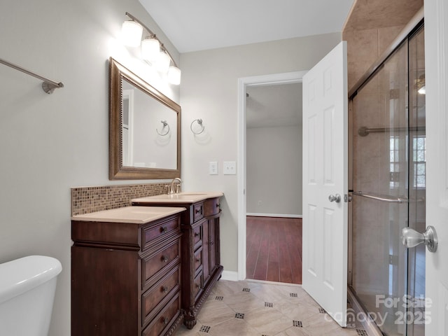 full bathroom with toilet, vanity, baseboards, a shower stall, and decorative backsplash