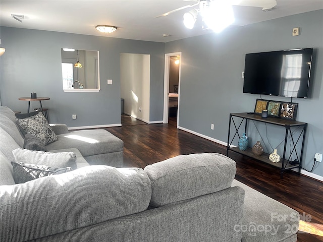 living room with ceiling fan, baseboards, and wood finished floors